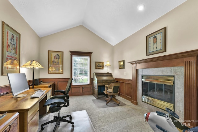office with a wainscoted wall, carpet flooring, a tile fireplace, and lofted ceiling