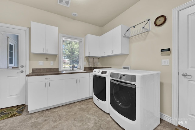 laundry room with visible vents, a sink, cabinet space, and washing machine and clothes dryer
