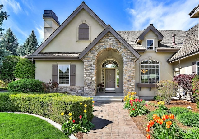 property entrance with a chimney, stucco siding, and stone siding