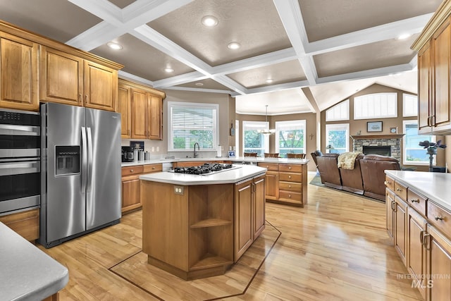 kitchen with light countertops, a stone fireplace, a center island, stainless steel appliances, and open floor plan
