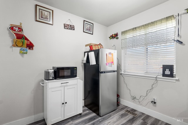 660 Teton, Mountain Home, ID 83647 - kitchen featuring wood finished floors, freestanding refrigerator, white cabinets, baseboards, and black microwave