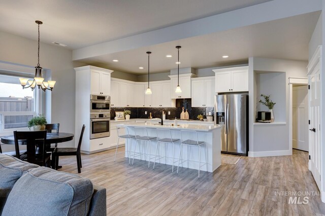 kitchen with appliances with stainless steel finishes, tasteful backsplash, open floor plan, a chandelier, and recessed lighting
