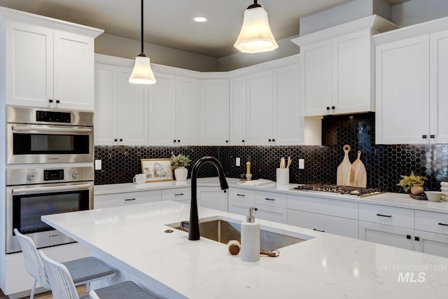 kitchen with stainless steel double oven, a sink, white cabinetry, and recessed lighting