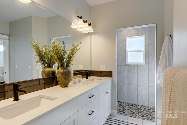 bathroom featuring tiled shower and double vanity