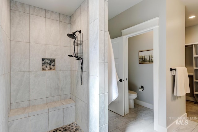 bathroom with tiled shower, toilet, tile patterned floors, baseboards, and recessed lighting