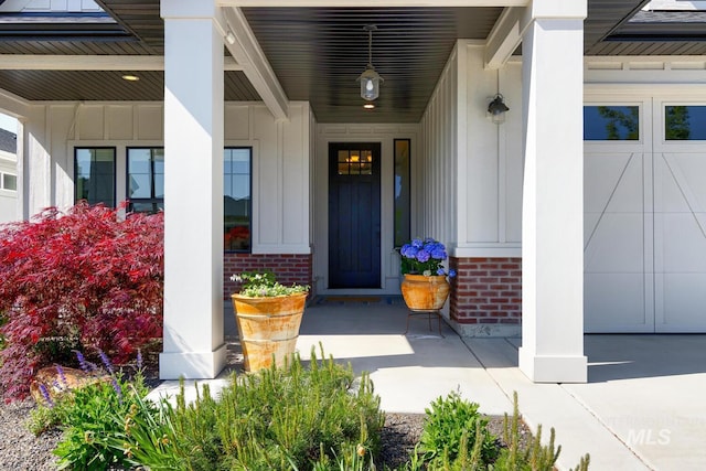 doorway to property featuring a porch, brick siding, and board and batten siding
