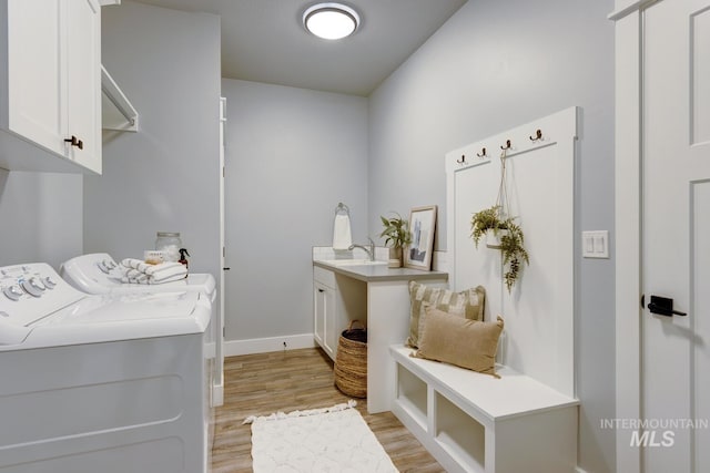 laundry area featuring cabinet space, washing machine and clothes dryer, light wood-type flooring, and baseboards