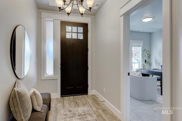 foyer entrance with a chandelier, light wood finished floors, and baseboards