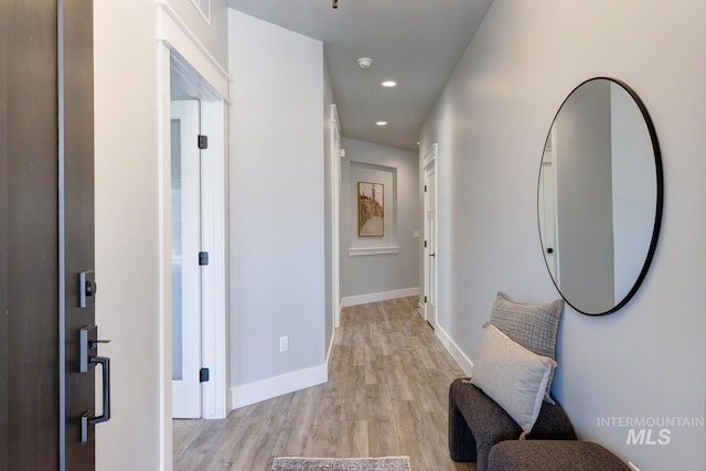 hallway featuring light wood-style floors, baseboards, and recessed lighting