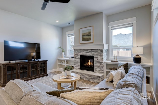 living area featuring a ceiling fan, a fireplace, wood finished floors, baseboards, and recessed lighting