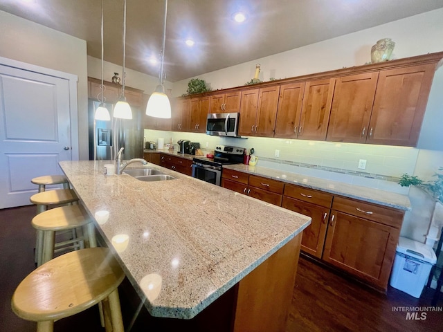 719 W Arbor Pointe, Nampa, ID 83686 - kitchen featuring stainless steel appliances, dark wood-style flooring, a breakfast bar, a center island with sink, and brown cabinetry