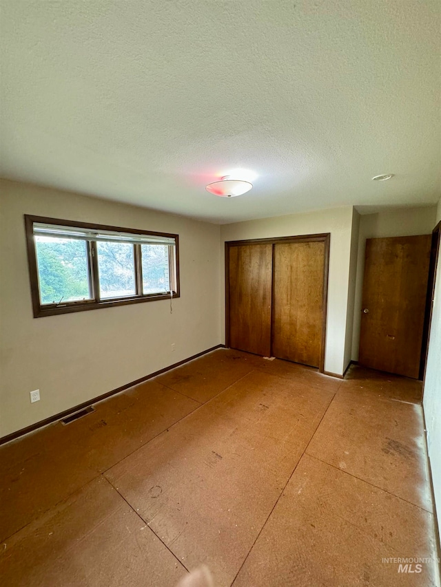 unfurnished bedroom featuring a textured ceiling and a closet