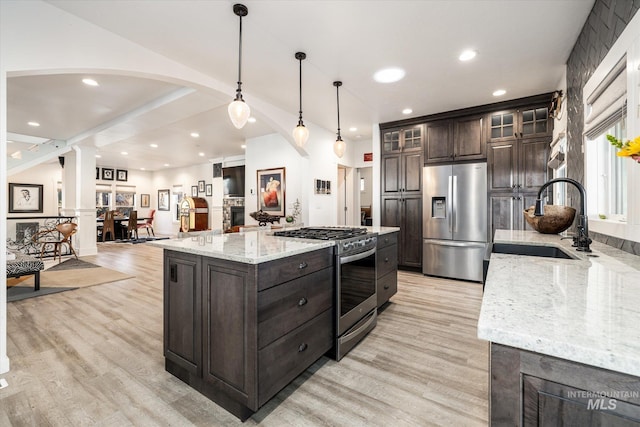 kitchen with a spacious island, pendant lighting, sink, stainless steel appliances, and dark brown cabinets