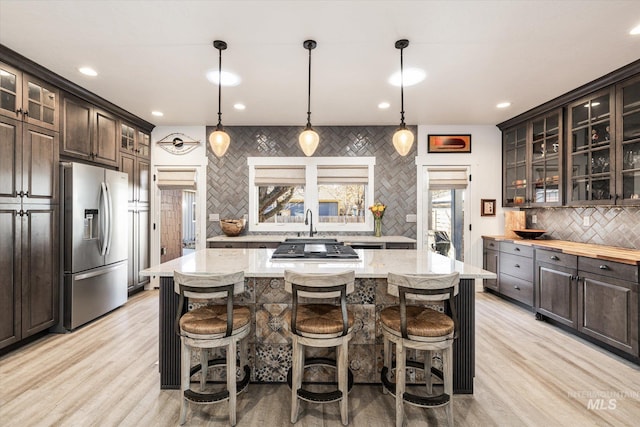 kitchen with appliances with stainless steel finishes, dark brown cabinetry, and a kitchen island