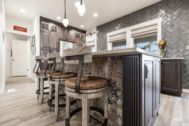 kitchen featuring hanging light fixtures, kitchen peninsula, a kitchen bar, and dark brown cabinetry