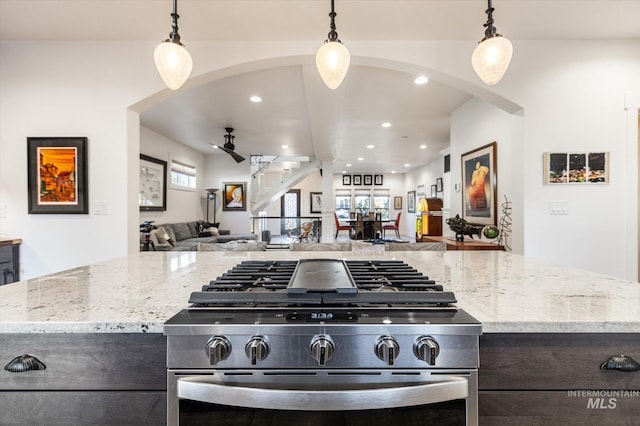 kitchen featuring gas range, pendant lighting, and light stone countertops