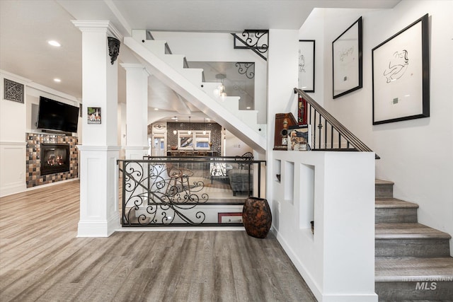 stairs featuring wood-type flooring and ornate columns