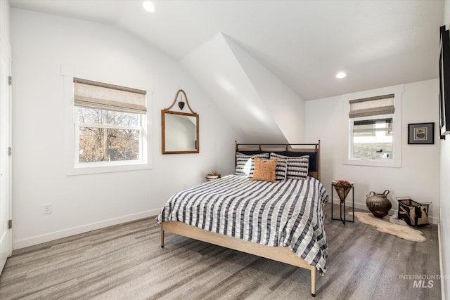 bedroom with vaulted ceiling, wood-type flooring, and multiple windows