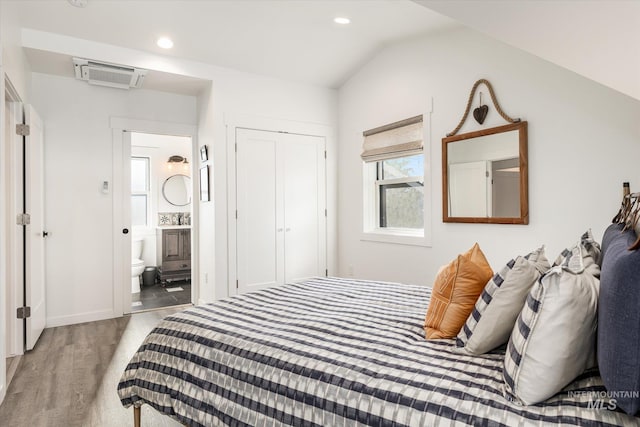 bedroom featuring vaulted ceiling, a closet, connected bathroom, and wood-type flooring