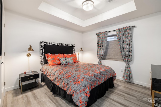 bedroom with a tray ceiling and hardwood / wood-style floors