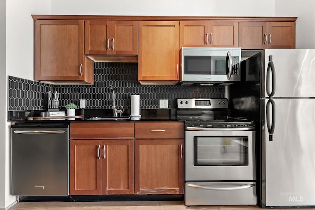 851 W Front St Unit 607, Boise, ID 83702 - kitchen with stainless steel appliances, a sink, dark countertops, decorative backsplash, and brown cabinetry