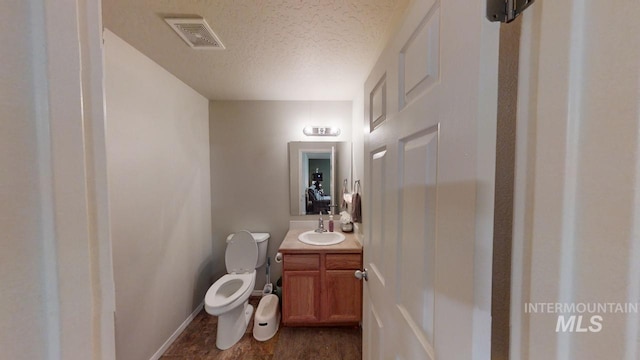 bathroom featuring toilet, a textured ceiling, and vanity