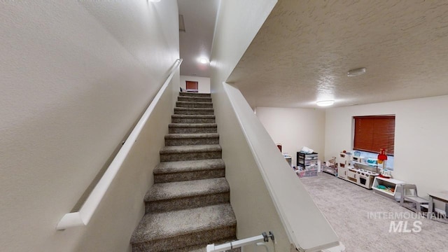 stairs featuring a textured ceiling and carpet flooring