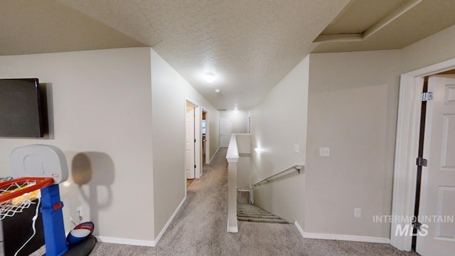 corridor with light carpet and a textured ceiling