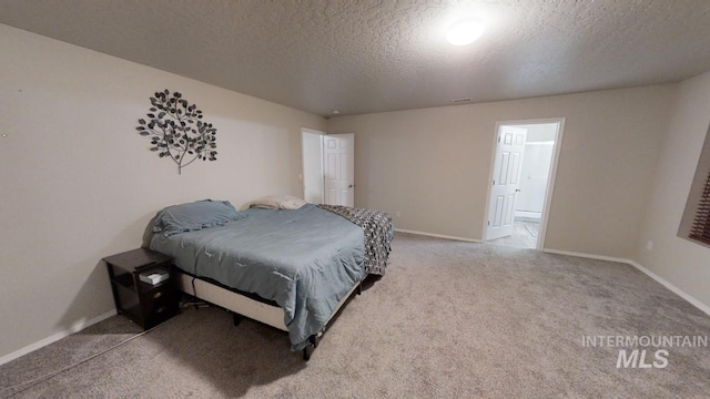 carpeted bedroom with a textured ceiling and connected bathroom