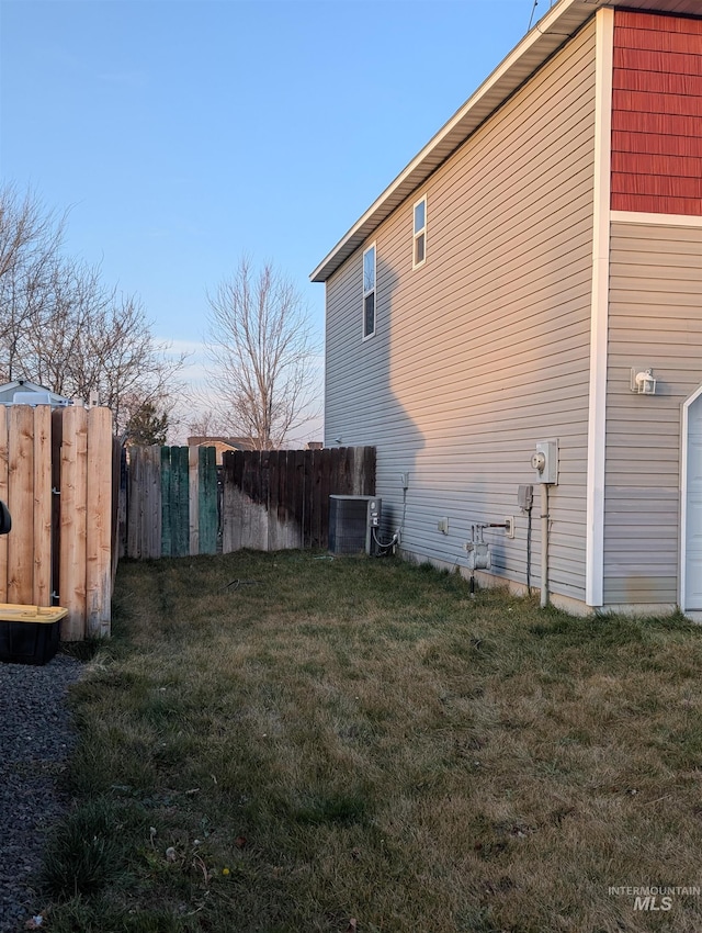 view of side of home with central air condition unit and a yard