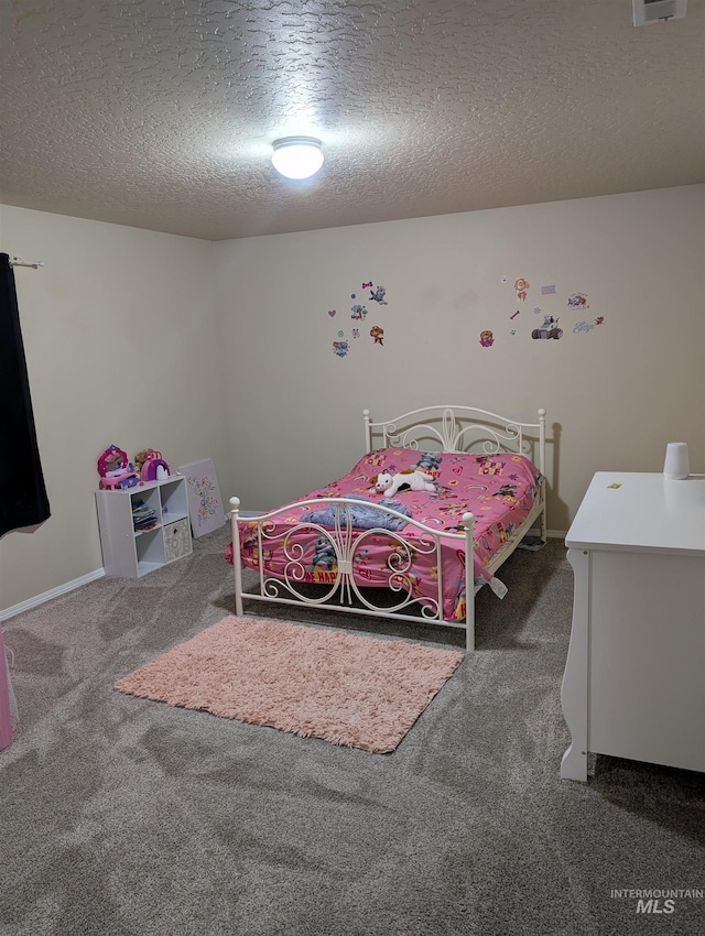 bedroom with a textured ceiling and dark carpet