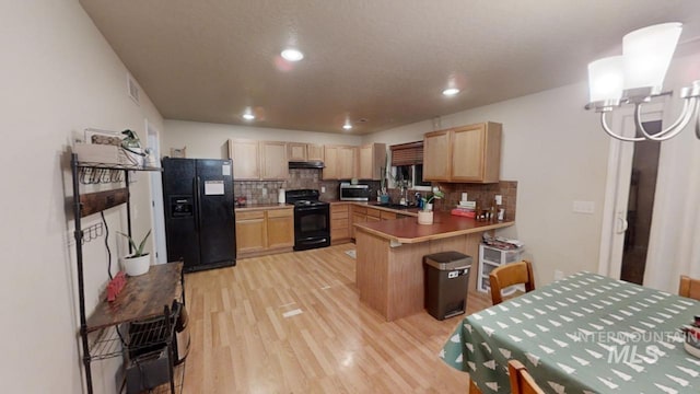 kitchen with kitchen peninsula, a kitchen bar, light brown cabinets, and black appliances