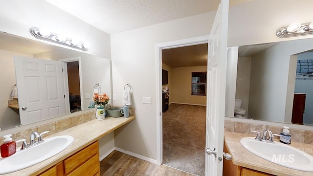 bathroom with a textured ceiling, toilet, hardwood / wood-style floors, and vanity