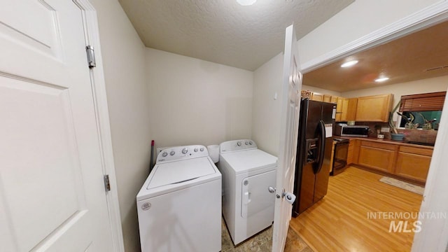 laundry area featuring washer and dryer, a textured ceiling, and light hardwood / wood-style flooring