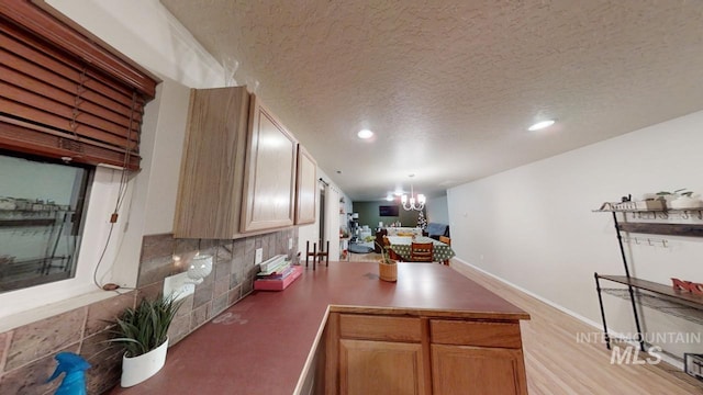 kitchen with a textured ceiling, a chandelier, pendant lighting, and backsplash