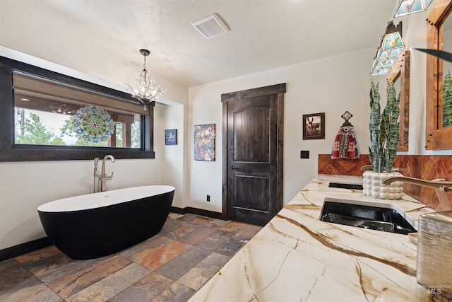 14051 Deerfield Rd, Mccall, ID 83638 - bathroom with stone tile floors, a freestanding bath, a chandelier, and vanity