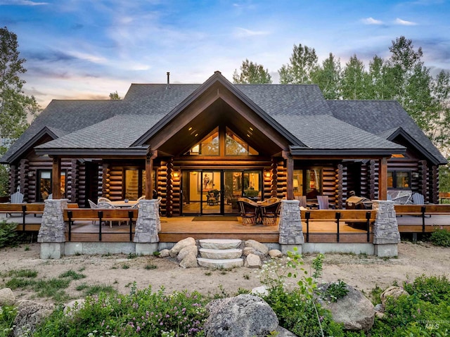 14051 Deerfield Rd, Mccall, ID 83638 - back of house at dusk with log siding, a shingled roof, and covered porch