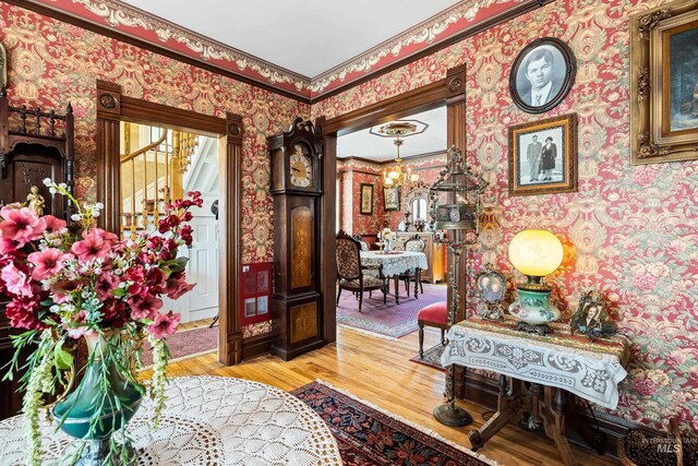 entrance foyer featuring ornamental molding, light hardwood / wood-style flooring, and a notable chandelier