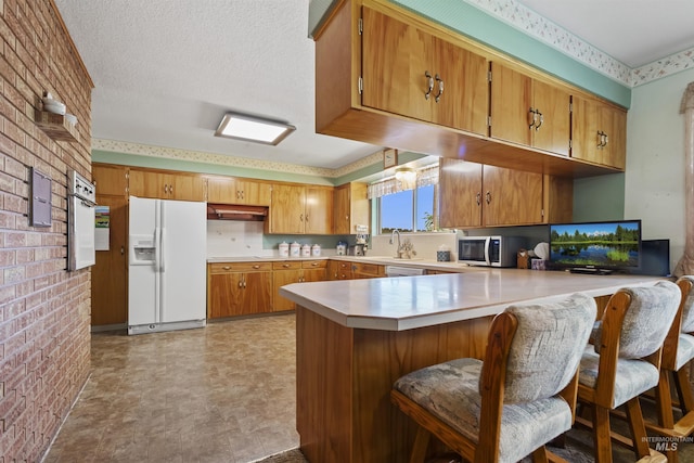 93 S Lancaster Dr, Nampa, ID 83651 - kitchen with white refrigerator with ice dispenser, stainless steel microwave, light countertops, a peninsula, and brown cabinets