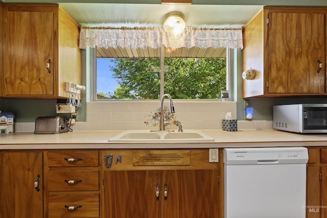 93 S Lancaster Dr, Nampa, ID 83651 - kitchen with white dishwasher, stainless steel microwave, a sink, brown cabinets, and backsplash