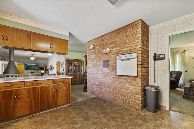 93 S Lancaster Dr, Nampa, ID 83651 - kitchen featuring wallpapered walls, brown cabinets, brick wall, light countertops, and a ceiling fan