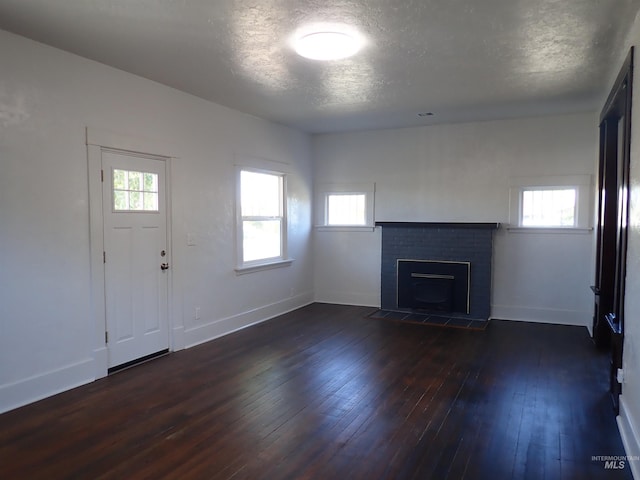 unfurnished living room with a brick fireplace, dark hardwood / wood-style flooring, and a textured ceiling