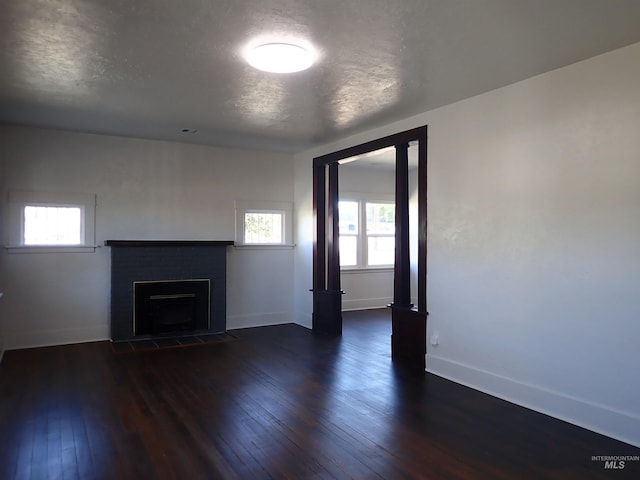 unfurnished living room featuring dark hardwood / wood-style flooring and a textured ceiling