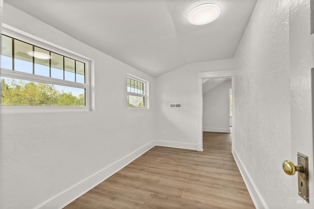 unfurnished room with lofted ceiling and light wood-type flooring