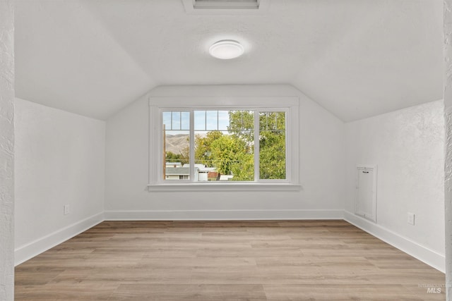 bonus room with light hardwood / wood-style floors, vaulted ceiling, and a textured ceiling