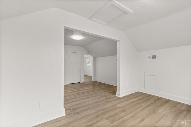 bonus room featuring vaulted ceiling, a textured ceiling, and light hardwood / wood-style floors