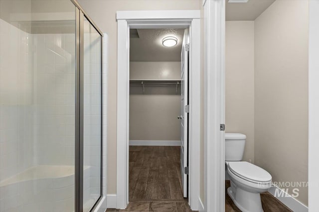 4991 N Sun Shimmer Ave, Meridian, ID 83646 - bathroom featuring a stall shower, a spacious closet, toilet, and baseboards
