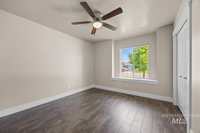 4991 N Sun Shimmer Ave, Meridian, ID 83646 - unfurnished bedroom with dark wood finished floors, baseboards, a closet, ceiling fan, and a textured ceiling