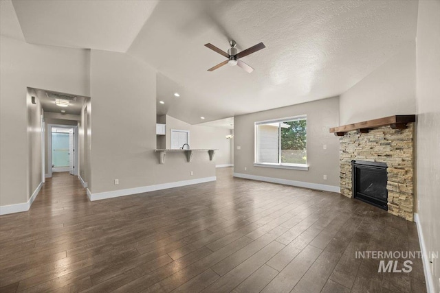 4991 N Sun Shimmer Ave, Meridian, ID 83646 - unfurnished living room featuring lofted ceiling, a ceiling fan, a stone fireplace, dark wood-style floors, and baseboards