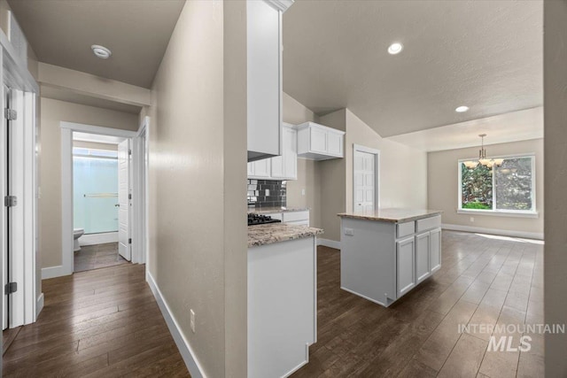 4991 N Sun Shimmer Ave, Meridian, ID 83646 - kitchen featuring dark wood-type flooring, white cabinets, tasteful backsplash, baseboards, and a kitchen island